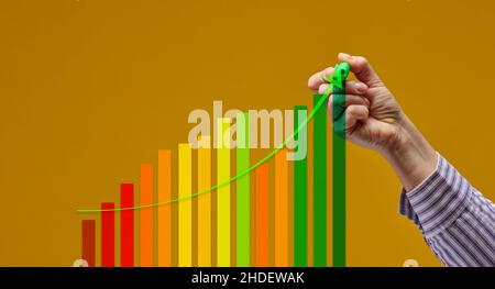 Weibliche Hand mit grünem Marker und mehrfarbiger Grafik auf gelbem Hintergrund. Konzept für das Leistungswachstum, positive Dynamik Stockfoto