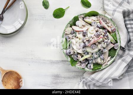 Hausgemachter waldorfsalat aus Apfelnuss und Spinat mit cremigem Dressing. Gesunde vegetarische Ernährung Konzept über einem rustikalen weißen Holzhintergrund. Stockfoto