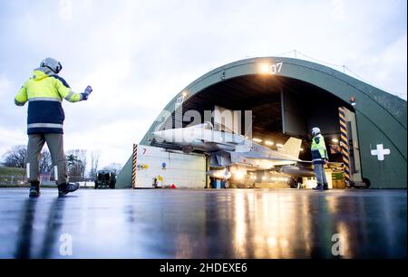 06. Januar 2022, Niedersachsen, Wittmund: Ein Kampfflugzeug der Luftwaffe Eurofighter Typhoon wird aus einem Hangar auf dem Luftwaffenstützpunkt Wittmundhafen vertrieben. Aufgrund einer umfassenden Sanierung des Flugstützpunktes in Wittmund, Ostfriesland, verlegt die Bundeswehr vorübergehend 19 Eurofighter von dort auf den Laage-Stützpunkt südlich von Rostock. Foto: Hauke-Christian Dittrich/dpa Stockfoto