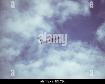 Flugzeug, das über dem Flughafen von Athen mit wolkig blauem Himmel fliegt Stockfoto
