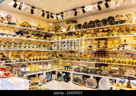 Türkisches traditionelles Geschäft (Souk) mit goldenem dekorativem Geschirr, Geschirr, Tellern, Tabletts, Tassen, Glas- und Teeservice im Global Village, Dubai. Stockfoto