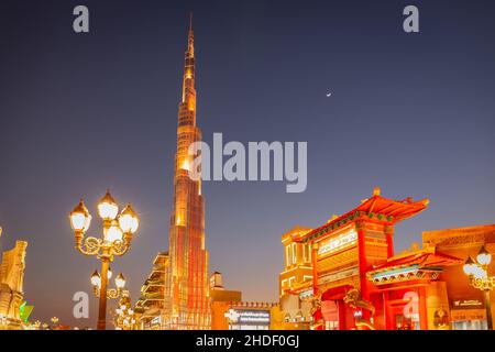 Dubai, VAE, 10.01.21. Global Village Vergnügungspark bei Nacht mit beleuchteten Burj Khalifa Miniatur und Pagoden, Halbmond am Himmel, Kopierraum Stockfoto