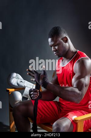 Der junge Afroamerikaner packte seine Hand mit einem Verband, während er sich auf ein Match vorbereitete. Stockfoto