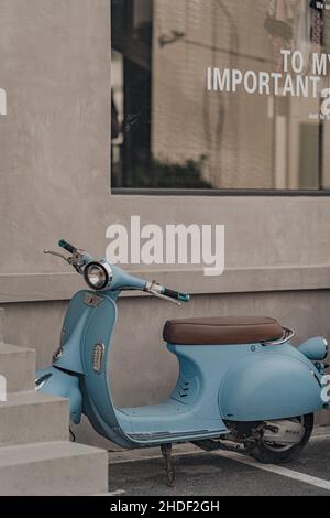 Vertikale Aufnahme eines blauen Motorrollers, das an einer Straße geparkt ist Stockfoto