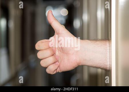 Die Hand eines Mannes rammte mit erhobenem Daumen aus dem Fahrzeugfach. Stockfoto