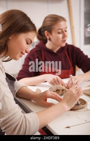 Vertikale Aufnahme einer schönen Frau, die lächelt und Spaß daran hat, im Keramikstudio mit Ton zu arbeiten Stockfoto