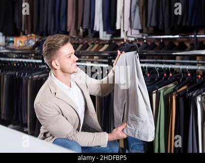 Männlicher Kunde, der Hosen im Geschäft für Männertücher untersucht Stockfoto