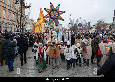 Warschau, Warschau, Polen. 6th Januar 2022. Ein Mann, der von Kindern in traditioneller Kleidung umgeben ist, trägt einen Stern während der Epiphaniefeier am 6. Januar 2022 in Warschau, Polen. Trotz der steigenden Anzahl von SARS-CoV2-Infektionen (Coronavirus) versammelten sich in der Altstadt Hunderte von Menschen, um den Dreikönigstag zu feiern, der in Polen auch als drei-Könige-Tag bekannt ist. (Bild: © Aleksander Kalka/ZUMA Press Wire) Stockfoto