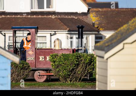 Der Lokführer fährt an Strandhütten auf der schmalen Hayling Seaside Railway, Hayling Island, Hampshire, Großbritannien Stockfoto