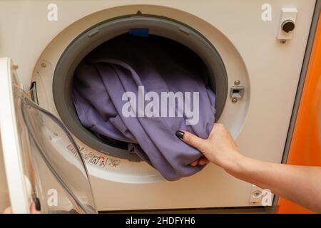 Die Hand der Frau zieht die Wäsche aus der Waschmaschine Stockfoto