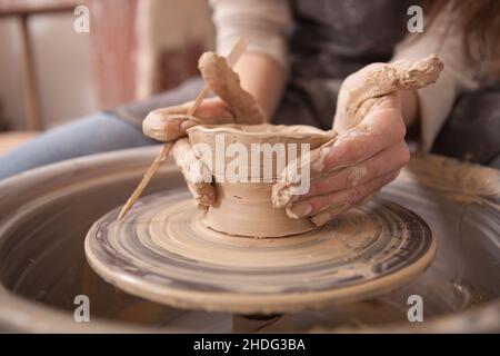 Nahaufnahme der weiblichen Hände einer Künstlerin, die eine Keramikschale auf dem Töpferrad macht Stockfoto