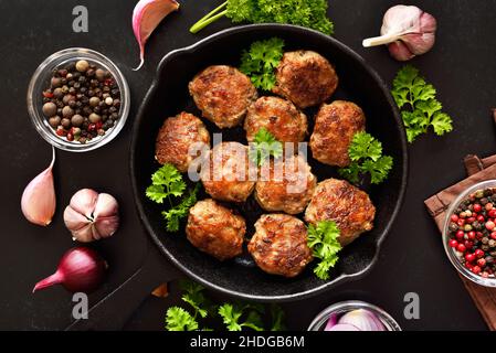 Hausgemachte Koteletts aus Hackfleisch in einer Pfanne auf schwarzem Hintergrund. Draufsicht, flach liegend Stockfoto