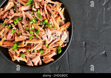 Langsam zog gekocht Rindfleisch für Sandwiches mit Petersilie auf einer Platte am Schwarzen Stein Hintergrund mit kopieren. Ansicht von oben, flach Stockfoto