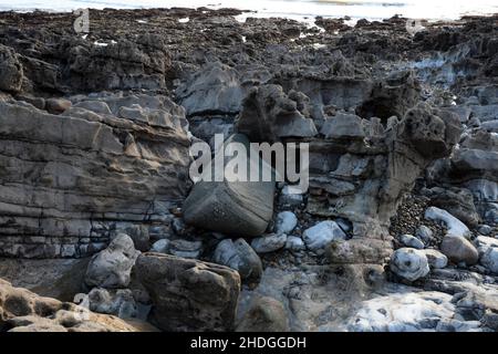 Ein unregelmäßiger Felsbrocken an einem nach Westen gerichteten Gower-Ufer, der durch Eisfluss von der Quelle möglicherweise Preseli Hills verschoben und am Ende der Eiszeit abgelagert wurde Stockfoto