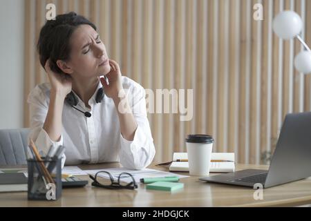 Die Dame am Call Center, die überfordert ist, leidet unter Müdigkeit und Nackenschmerzen Stockfoto