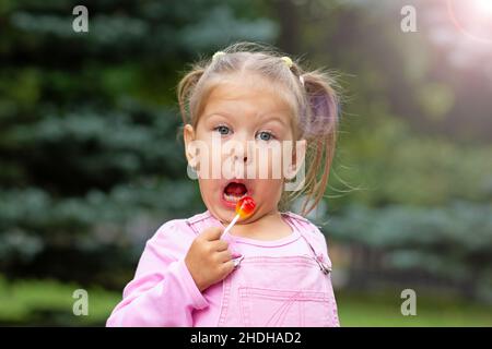 Schönes Kind mit lustigen Gesicht lecken Lollipop Stockfoto