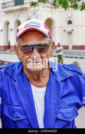 Porträt eines kubanischen Mannes, der einen blauen Overall, eine Sonnenbrille und eine Baseballmütze mit der Nationalflagge trägt. Januar 6, 2022 Stockfoto