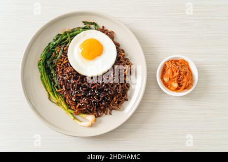 Hausgemachte getrocknete koreanische, würzige, schwarze Soße, Instant-Nudeln mit Spiegelei und Kimchi Stockfoto