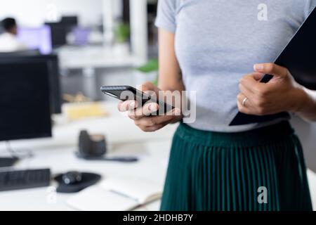 Mittelteil der Geschäftsfrau mit smart phone in kreative Büro Stockfoto