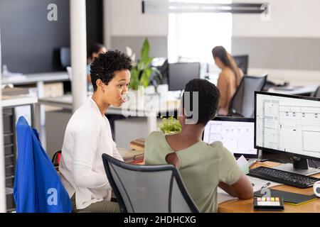 Architektinnen mit Bauplänen am Computer diskutieren am Schreibtisch im Kreativbüro Stockfoto