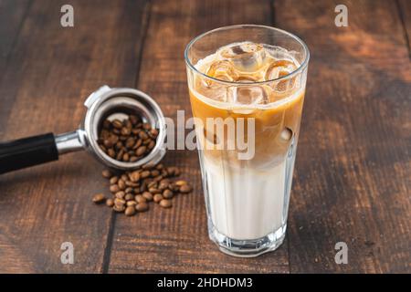 Eine Tasse Iced Latte Coffee mit Eiswürfeln auf einem Holztisch in einem Café Stockfoto