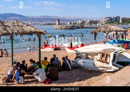 Menschen Vor Ort, Die Am Öffentlichen Strand In Aqaba, Im Gouvernement Aqaba, Jordanien, Sitzen. Stockfoto