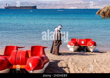 Ein Paar aus Jordanien mittleren Alters, das am öffentlichen Strand von Aqaba, Governorat Aqaba, Jordanien, spazieren geht. Stockfoto