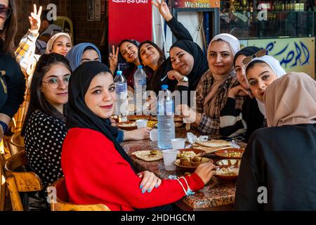 Eine Gruppe junger jordanischer Frauen genießt das Frühstück vor einem Café in Aqaba, Governorate Aqaba, Jordanien. Stockfoto