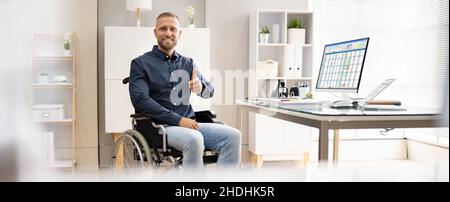 Glücklicher Junger Arbeiter Mit Behinderung, Der Computer Verwendet Stockfoto