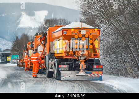 Liptovsky Hradok, Slowakei - 12. Februar 2020: Gruppe von hellorangen Straßenmeisterwagen mit Eisensalz, die sich im Winter vorbereiten, Schneekoje Stockfoto