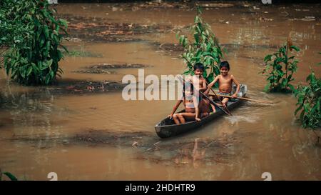 Indigene Kinder rudern den Amazonas entlang, Ecuador Stockfoto