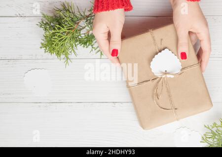 Die Hände der Frau halten ein Weihnachtsgeschenk. Draufsicht Stockfoto