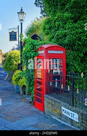 Großbritannien, West Yorkshire, Haworth, Main Street, Red Telephone Box und Haworth Old Hall Inn Schild Stockfoto