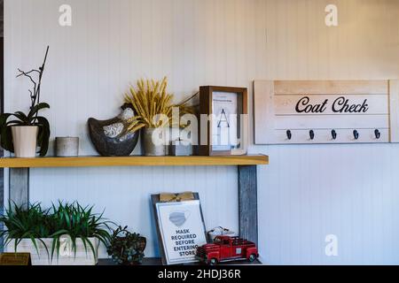 Regale mit Dekoration und Pflanzen. An der weißen Wand hängendes Garderobenregal Stockfoto