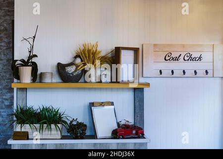 Regale mit Dekoration und Pflanzen. An der weißen Wand hängendes Garderobenregal Stockfoto