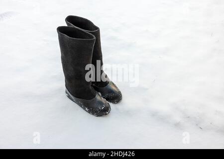 Nahaufnahme von warmen Filzstiefeln mit Gummigaloshen, die an einem frostigen Wintertag im Schnee stehen. Schweden. Stockfoto