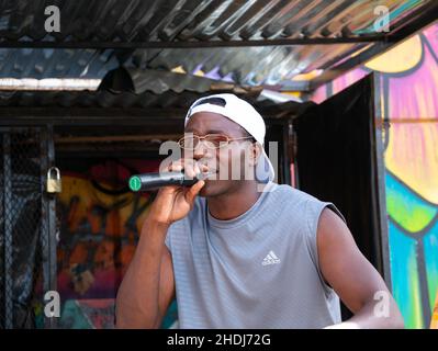 Medellin, Antioquia / Kolumbien - September 9 2021: Schwarzer weiblicher Rapper in Weiß mit Bandana-Gesang in Mikrofon in der Comuna 13, touristisch Stockfoto