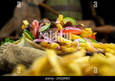 Griechische Gyros, eingewickelt in Pita-Brot auf einem Holzbrett in einer rustikalen Küche Stockfoto