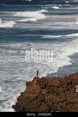 Seeangler, riskieren ihr Leben, die Fischerei auf Brassen aus einer prekären Position auf einem Felsen, mit Blick auf den wilden Atlantischen Ozean Stockfoto