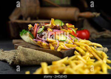 Griechische Gyros, eingewickelt in Pita-Brot auf einem Holzbrett in einer rustikalen Küche Stockfoto