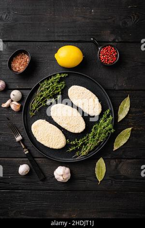 Rundes Set mit frischen Fischkuchen, auf schwarzem Holztisch-Hintergrund, Draufsicht flach liegend Stockfoto