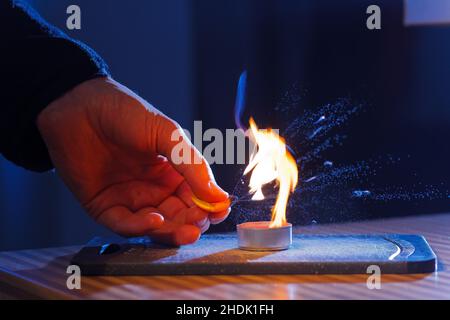 Brennbare Öle in Orangenschalen brennen, wenn sie in eine Kerzenflamme gepresst werden Stockfoto