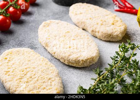 Ein frisches rohes Fischkuchen-Patties-Set, auf grauem Steintisch-Hintergrund Stockfoto