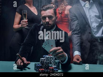 Reich schöner Mann rauchen Zigarre und Spielen im Casino Stockfoto