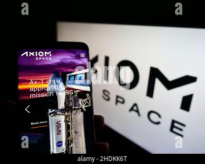 Person, die Mobiltelefon mit der Website des amerikanischen Luft- und Raumfahrtunternehmens Axiom Space Inc. Auf dem Bildschirm vor dem Logo hält. Konzentrieren Sie sich auf die Mitte des Telefondisplays. Stockfoto