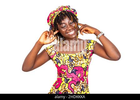 Schöne junge Frau, die traditionelle Lendenschurz trägt und die Ohren mit den Fingern bedeckt und lächelt. Stockfoto