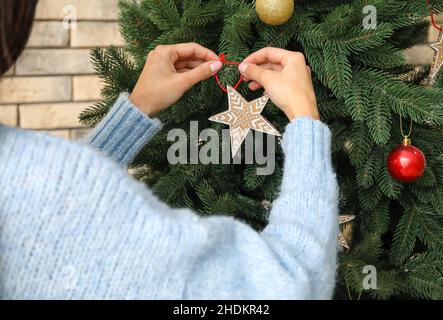 Frau hängend Pappstern auf Weihnachtsbaum, Nahaufnahme Stockfoto