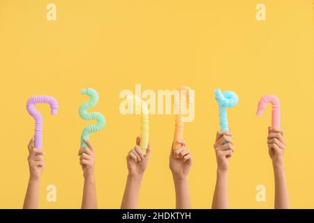 Hände mit beliebten Pop-Tubes auf farbigem Hintergrund Stockfoto