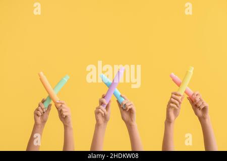 Hände mit beliebten Pop-Tubes auf farbigem Hintergrund Stockfoto