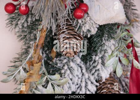Weihnachtliche Dekoration mit Schnee, Evergreens, Kegelbällen und Feiertagsmotiven. Goldenes und rotes Band. Frohes neues Jahr und frohe Weihnachten. Stockfoto
